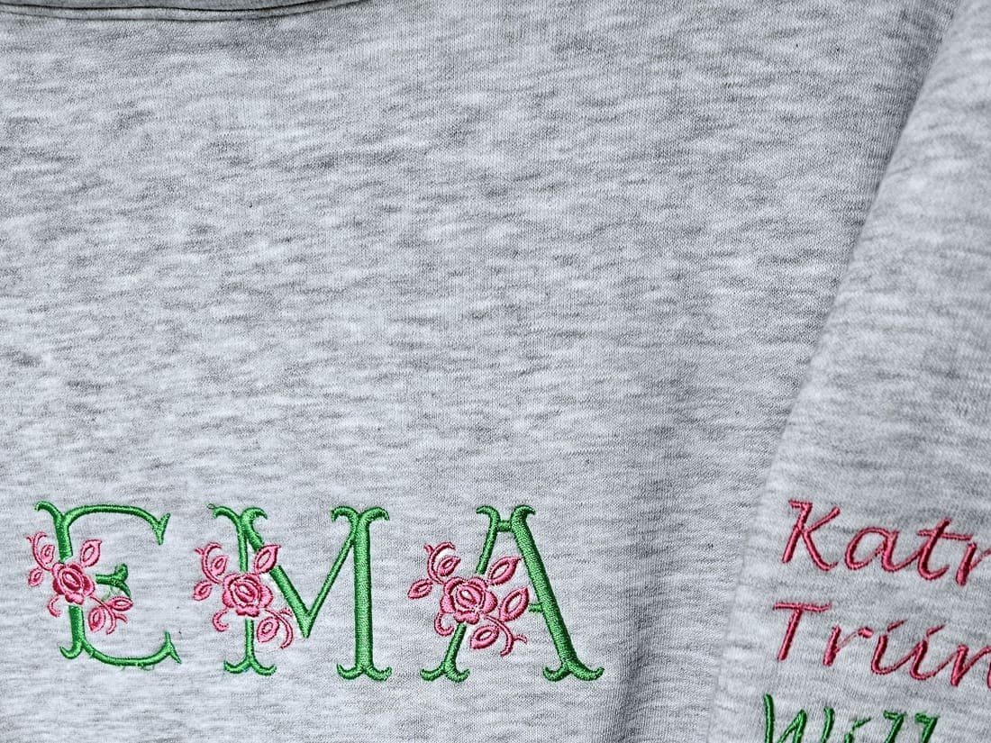 Hall pusa tikitud lillemonogrammiga ja nimedega varrukal